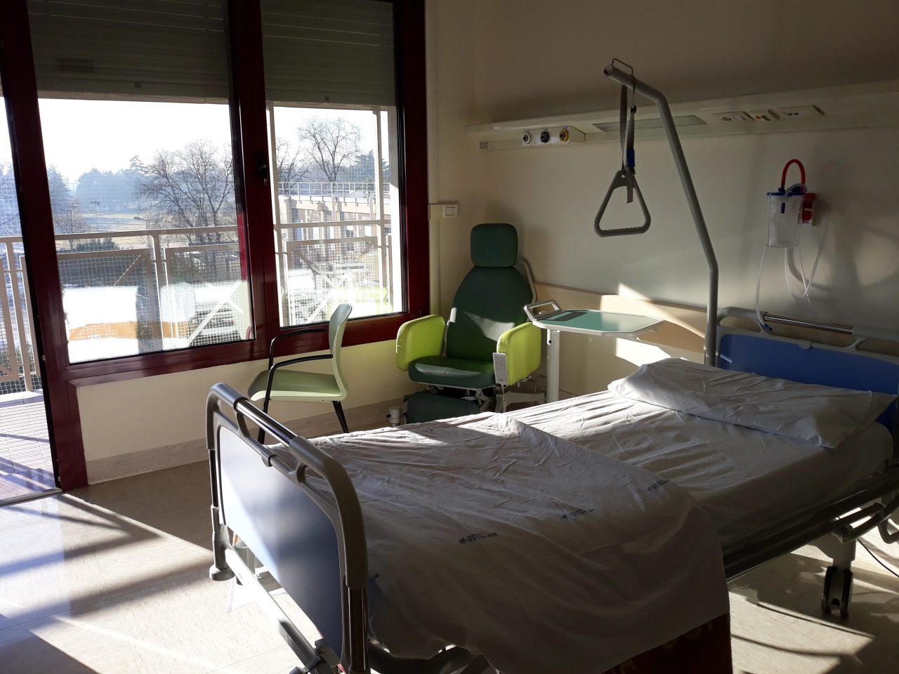 Stanza di degenza con letto, poltrona e affaccio sul parco del Policlinico G.B. Rossi