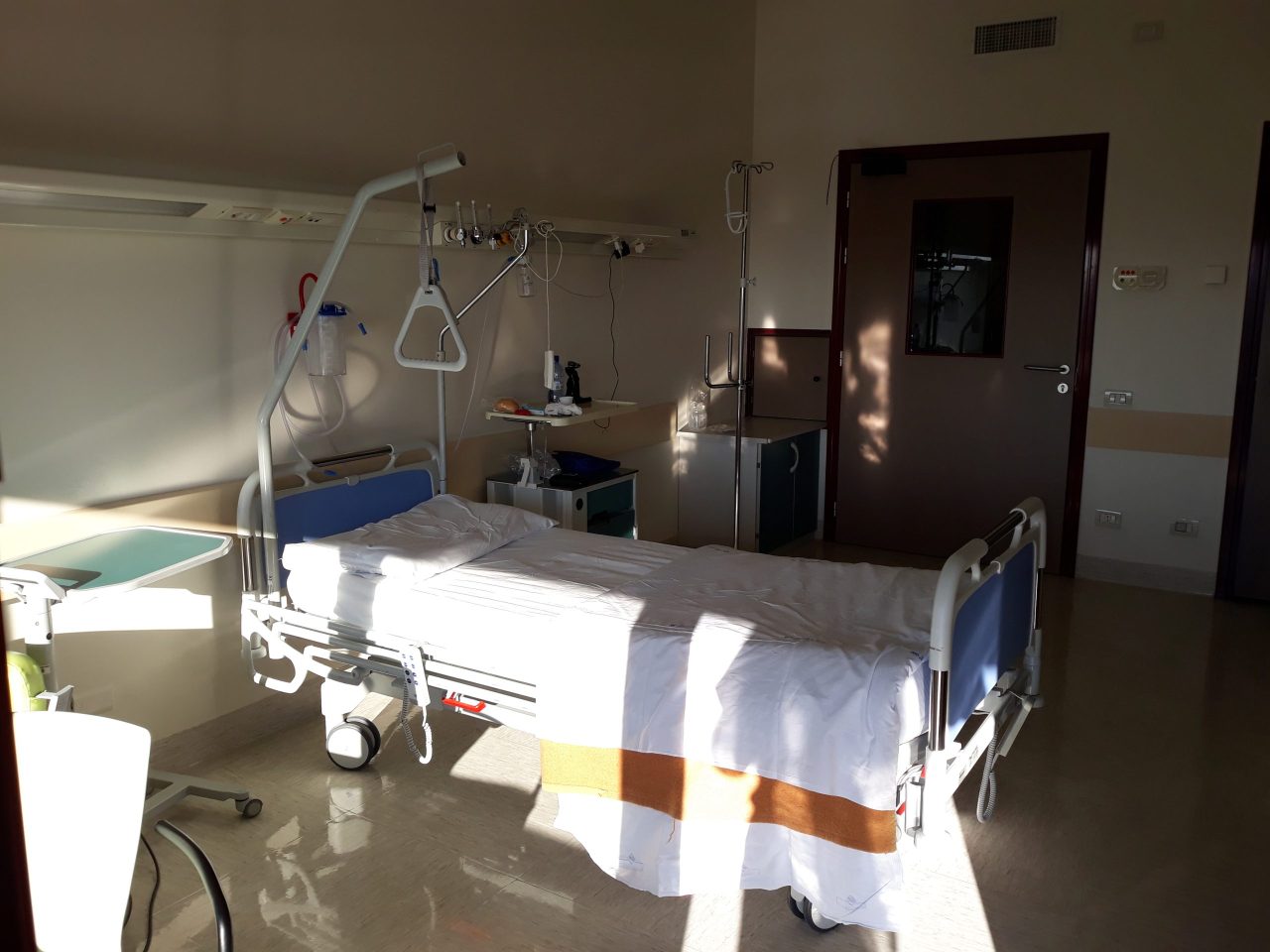Stanza di degenza del Policlinico G.B. Rossi con letto singolo, asta per flebo e porta sul corridoio